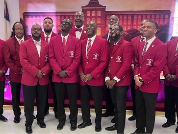 Group of men in matching red blazers and ties posing indoors.