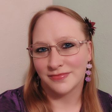 Woman with glasses and flower earrings smiling.
