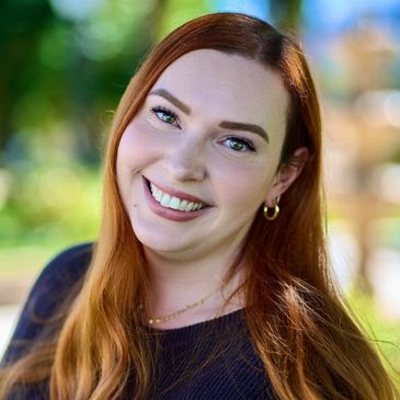 Smiling young woman with red hair outdoors.