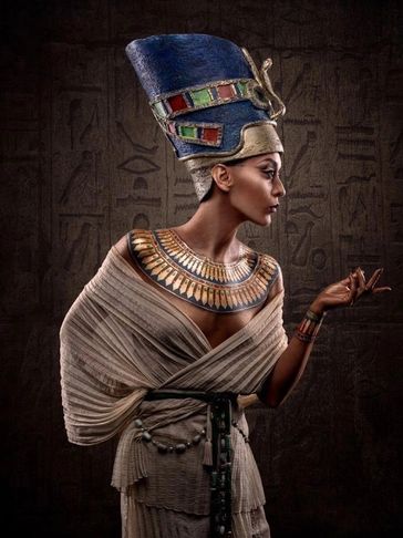 Woman dressed as ancient Egyptian queen with elaborate headdress and jewelry.