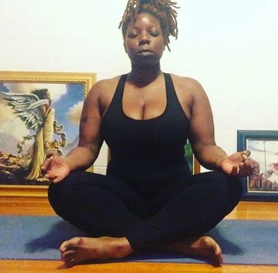 Woman meditating cross-legged indoors on a yoga mat.