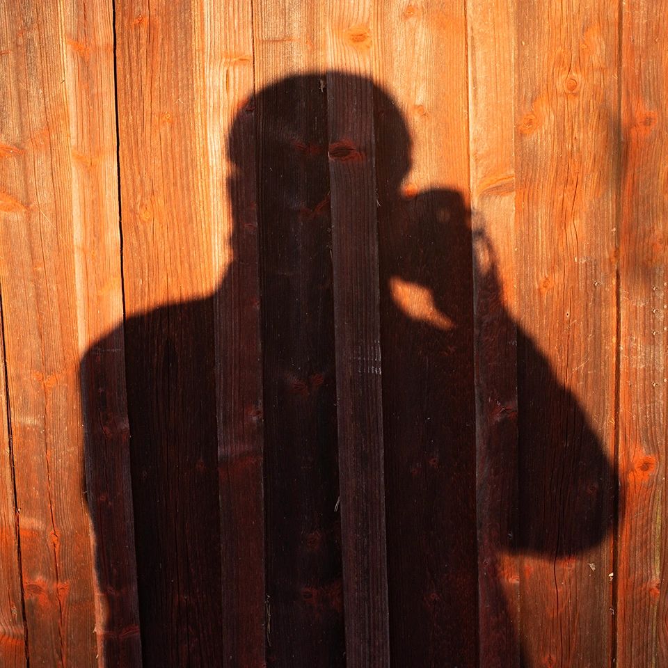 Shadow of a person taking a photo on a wooden fence.