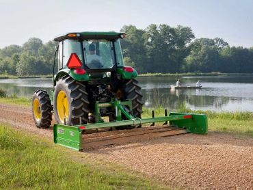 Tractor with a land plane, grading a gravel driveway.