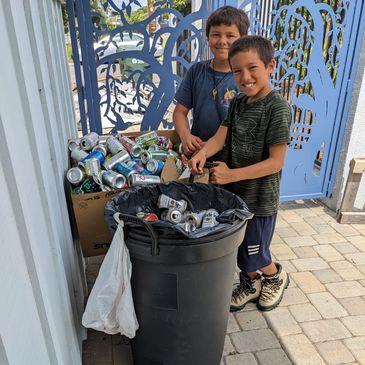 Two boys recycling aluminum cans with smiles.