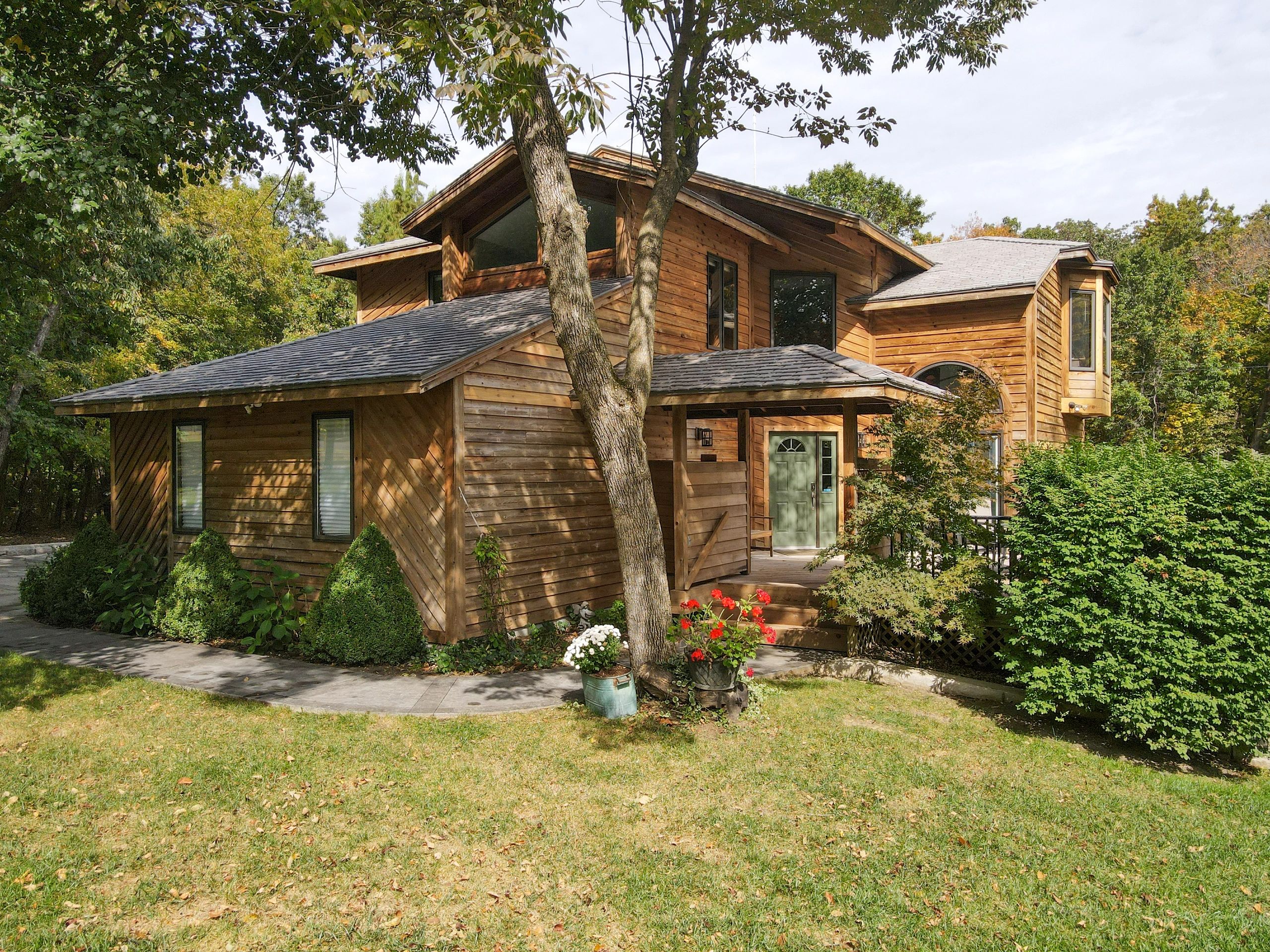 A charming wooden house surrounded by lush greenery and flowers.