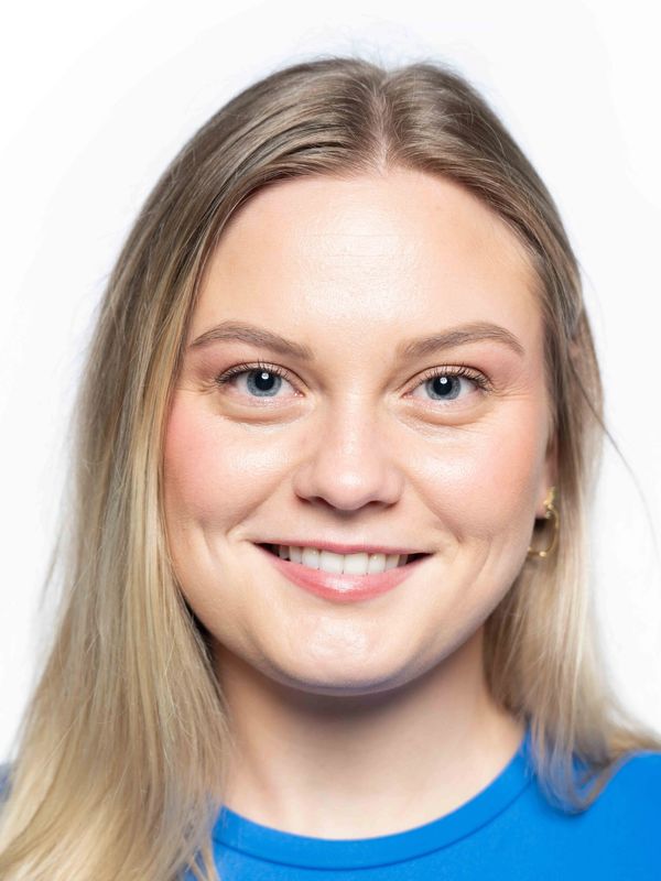 Close-up portrait of a smiling woman with blue eyes and blonde hair.