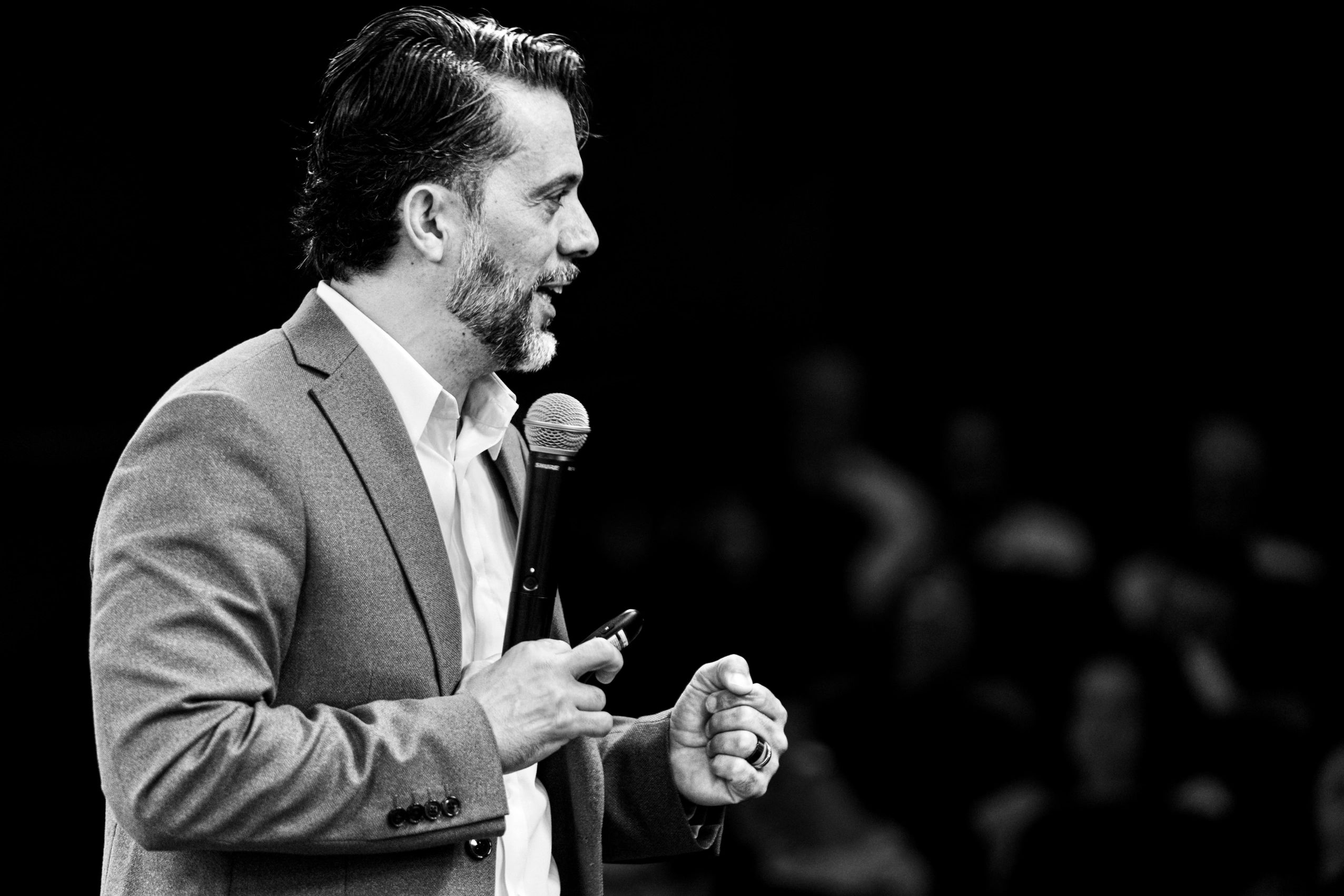 Man speaking energetically with a microphone in hand.