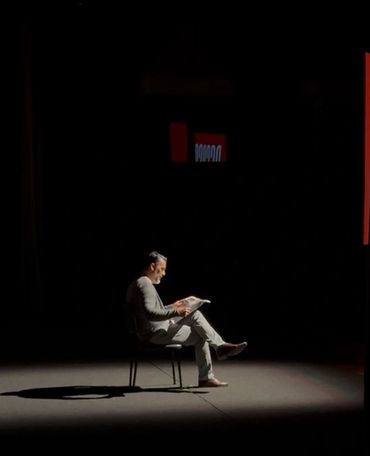 Allan sentado en una silla en el escenario