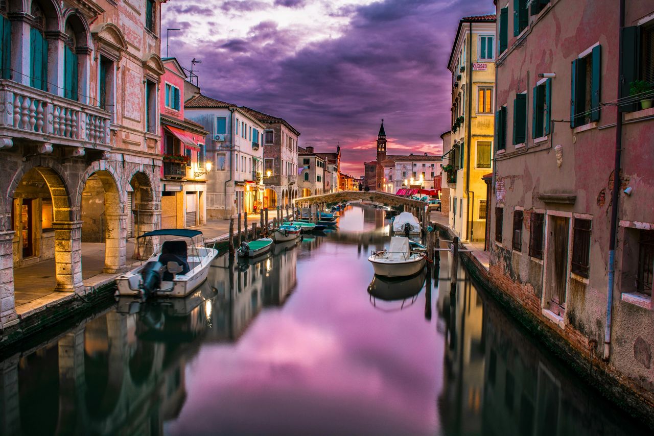 “Venice canal at sunset with colorful houses and reflections on the water.”