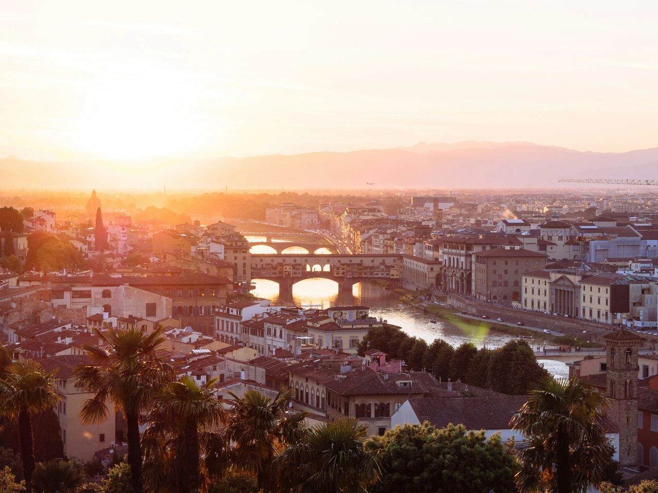 “Panoramic view of Florence, Italy at sunset with the Arno River, Ponte Vecchio, and historic city rooftops in autumn.”