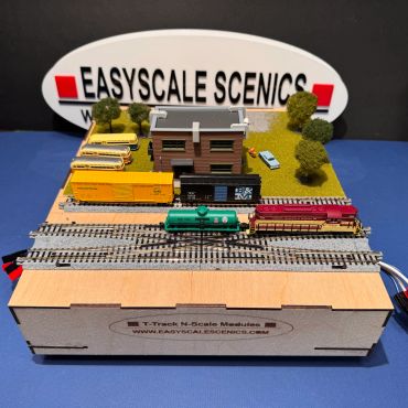 Miniature train set on a detailed model landscape with buildings and trees.