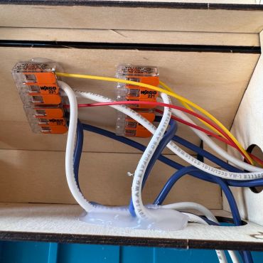 Electrical wires connected with orange Wago connectors inside a box.