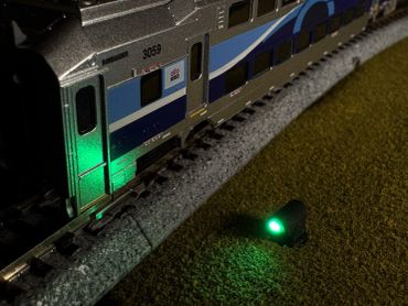A model train with green lights on a miniature track at night.