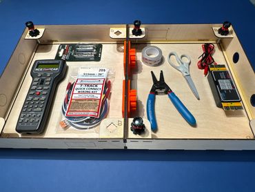 A wooden organizer holds electronic tools and components on a blue surface.