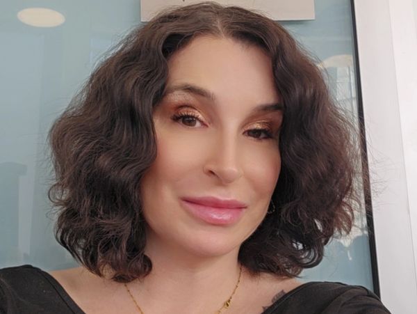 Woman with curly brown hair and soft makeup smiling at the camera.