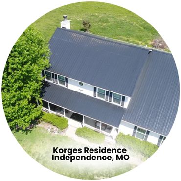 Aerial view of Korges Residence with black metal roof and lush greenery.
