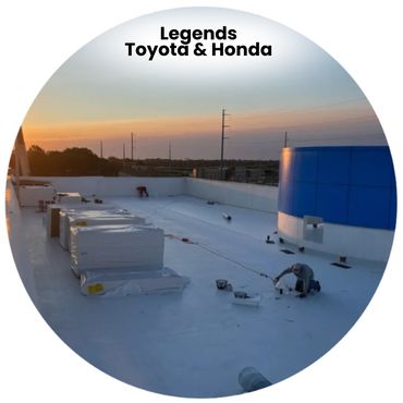 Workers installing roofing material on a large flat roof at sunset.