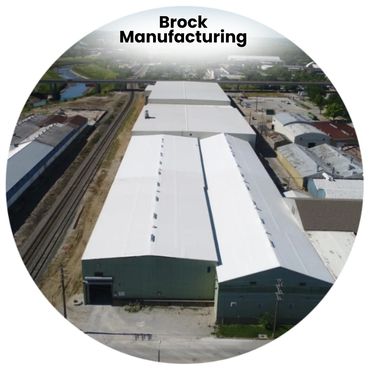 Aerial view of Brock Manufacturing's large industrial buildings beside railway tracks.