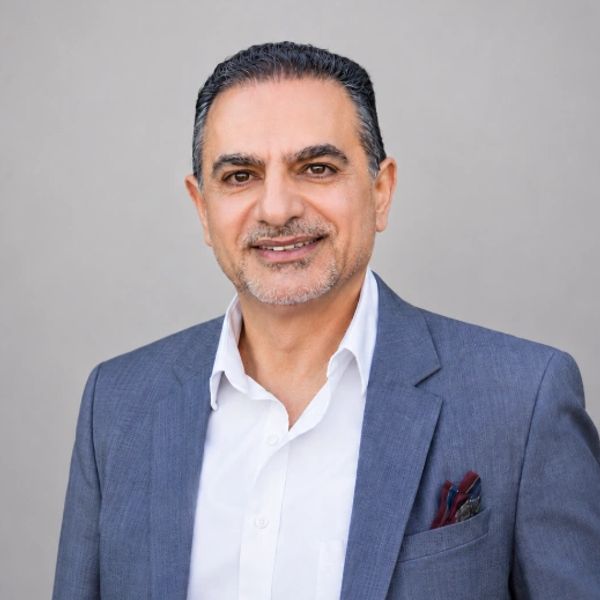 Smiling man in blue blazer and white shirt.