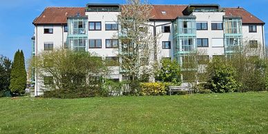 A residential building with balconies and a green lawn in front.