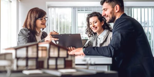 Couple meeting with a female real estate agent indoors.