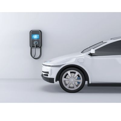 White electric car charging on a wall-mounted charger in a minimalistic setting.