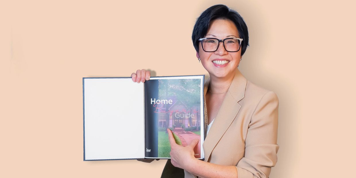 Smiling woman in glasses holding a home buying guide booklet.