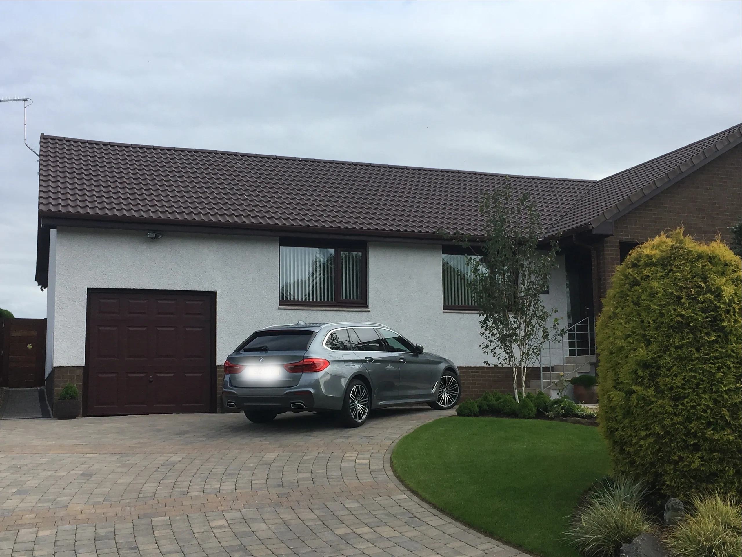 Modern house with a sleek gray car parked on the driveway.