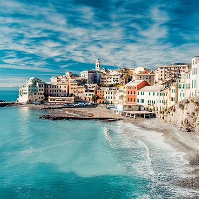 Picturesque coastal town with colorful buildings by the sea under a vibrant sky.