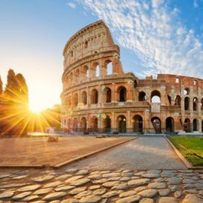 Sunrise over the ancient Colosseum in Rome with a clear blue sky.