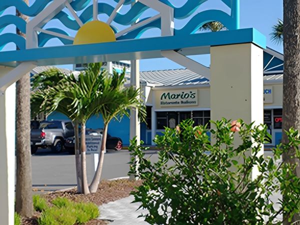 Entrance to Mario's Ristorante Italiano with tropical plants and a decorative arch.