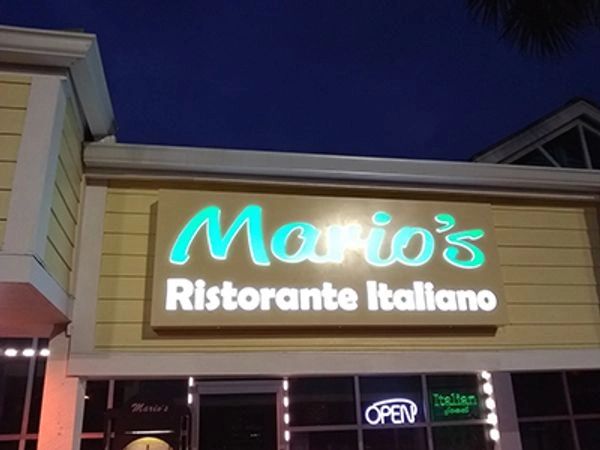 Illuminated sign for Mario's Italian restaurant at night.