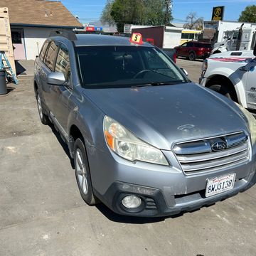 Silver Subaru Outback parked outdoors with a number 3 sign on the roof.