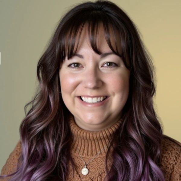 Smiling woman with long wavy purple hair and a brown sweater.