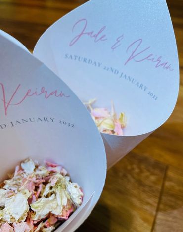 Paper Confetti Cones stood on a wooden table, filled with pink and white, dried, petal confetti.