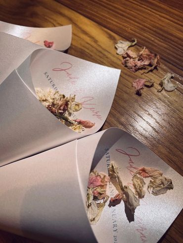 Paper Confetti Cones lay on a wooden table, filled with pink and white, dried, petal confetti.