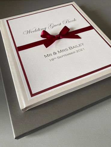 White Wedding Guest Book, with white & red front label and red ribbons and bow.
