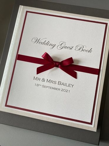 White Wedding Guest Book, with white & red front label and red ribbons and bow.