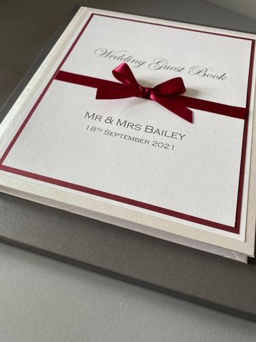 White Wedding Guest Book, with white & red front label and red ribbons and bow.