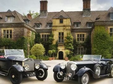 Llangoed Hall with 2 classic cars outside.