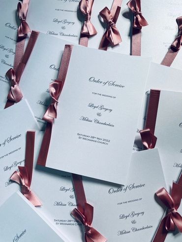 Set of wedding 'Order of Service' booklets, with pink ribbons and bows.