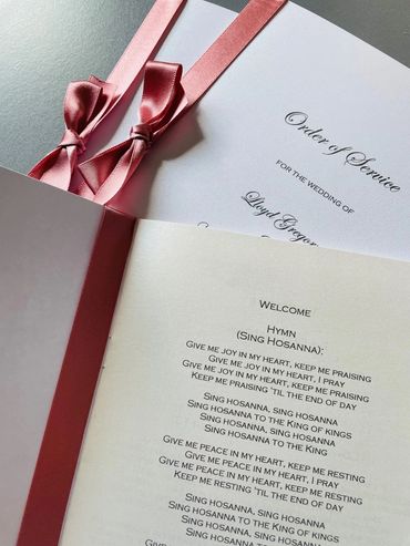 Set of wedding 'Order of Service' booklets, with pink ribbons and bows.