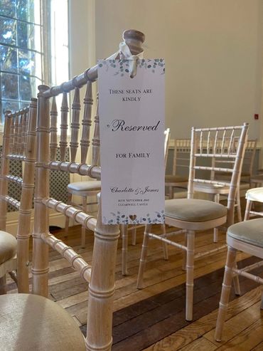 Reserved seating sign hanging on a wooden chair in a wedding ceremony room