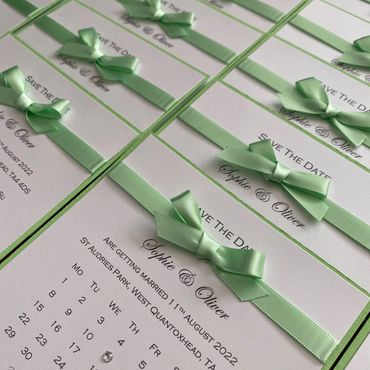 Set of White, Save the Date Invitations with green ribbon and bows.