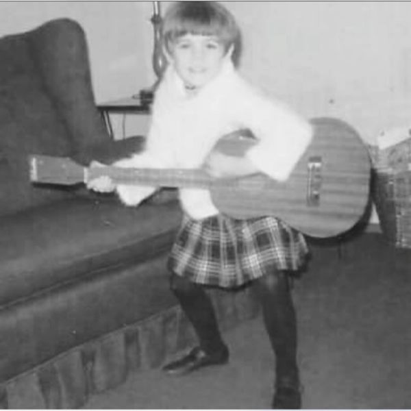 Child playing guitar in living room.