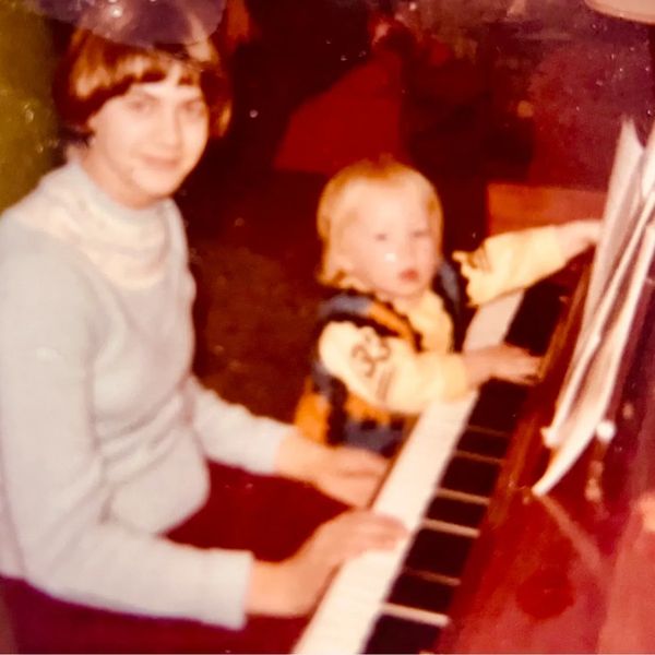 Adult and child playing piano together.