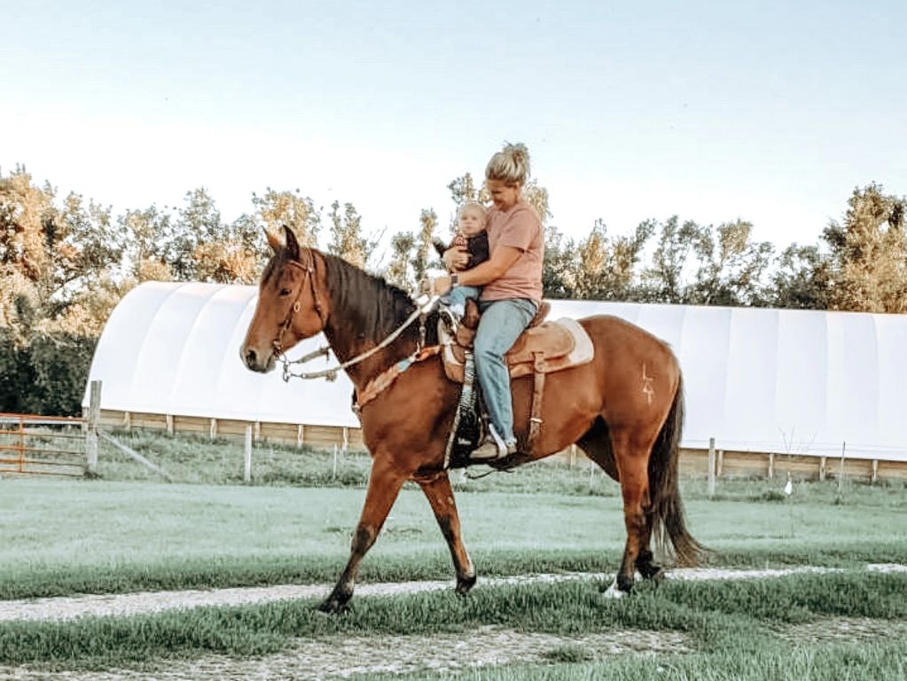 Woman and baby riding a horse.
