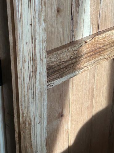Close-up of a wooden door with natural grain patterns and sunlight.
