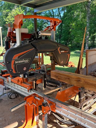 Norwood LumberPro sawmill cutting a wooden log outdoors.