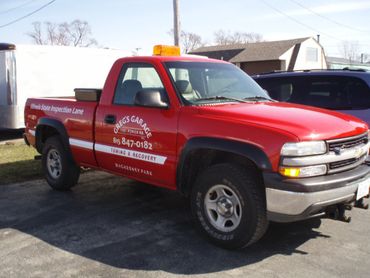 Red pickup truck with garage service signage parked outdoors.